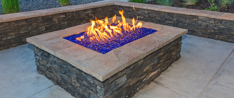A gas fire pit topped with blue rocks on a property in Easton, PA.