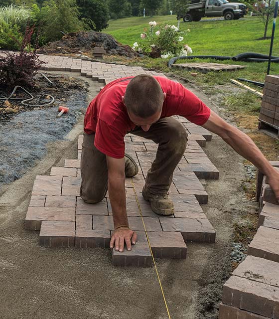 Landscape construction worker installing paver walkway in Clifton, NJ.