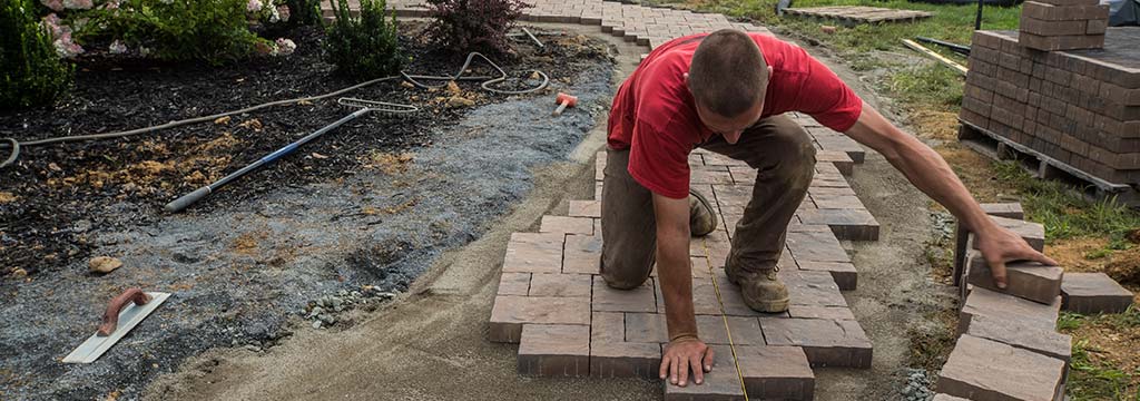 Landscape worker installing a custom paver walkway in Clifton, NJ.