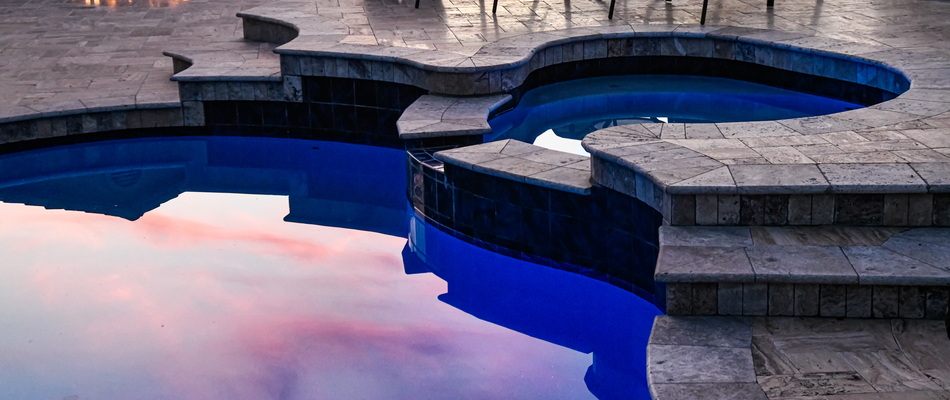 A pool surrounded by stone during sunset behind a home in Clinton, NJ.