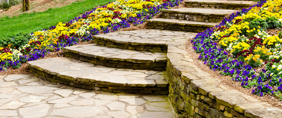 Stone steps and retaining wall surrounded by flowers installed on a sloped property in Bethlehem, PA.
