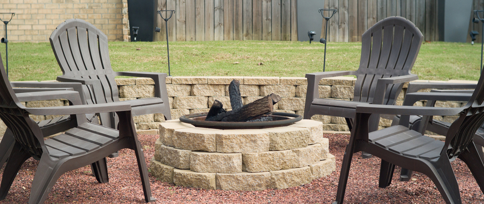 A wood burning fire pit built out of stone surrounded by chairs in our client's backyard in Nazareth, PA.