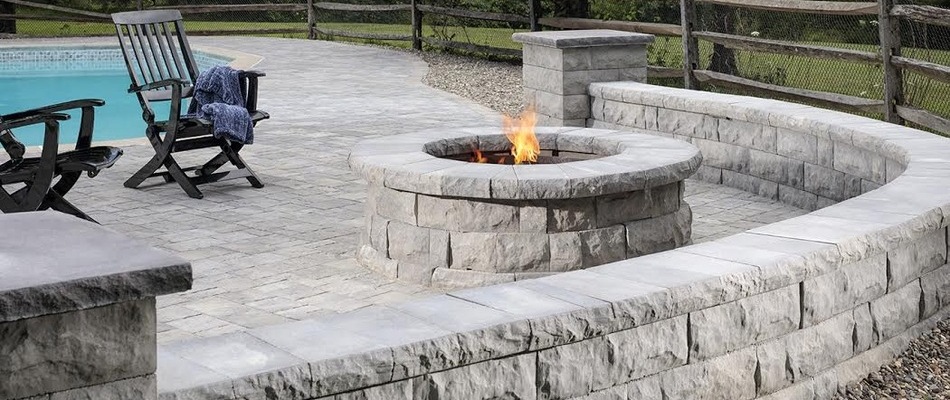 A concrete seating wall installed around a fire pit near a pool on a property in Stewartsville, NJ.